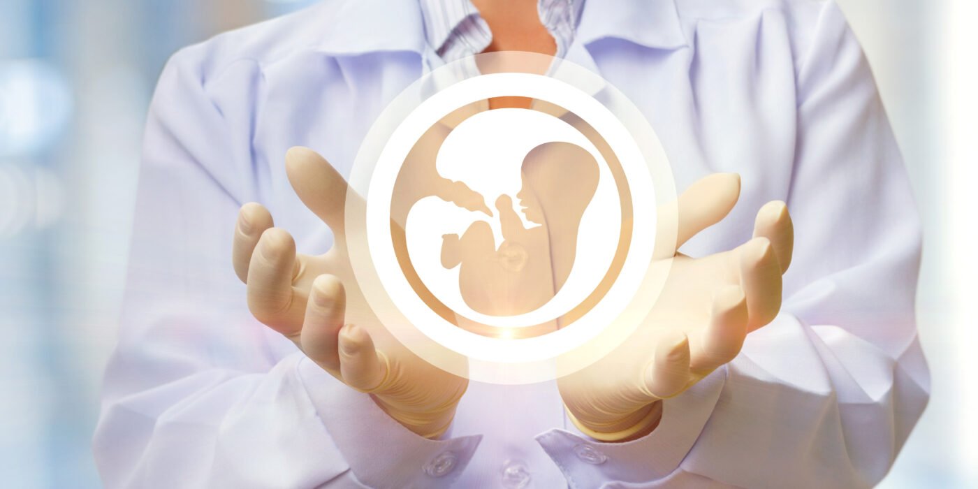 Ein Arzt in einem weißen Kittel und sterilen Handschuhen hält ein symbolisches Hologramm eines Embryos in den Händen, das den In-vitro-Fertilisation- und Embryotransfer-Prozess darstellt.