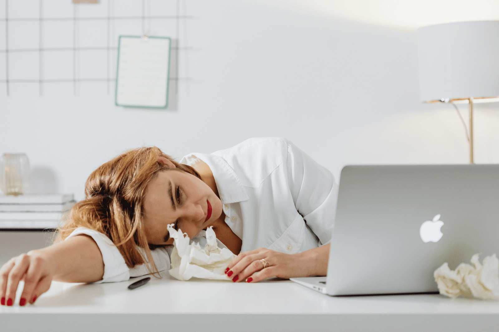 Erschöpfte Frau lehnt den Kopf auf den Tisch, Symbol für Stress bei der Vereinbarkeit von Kinderwunschbehandlung und Beruf