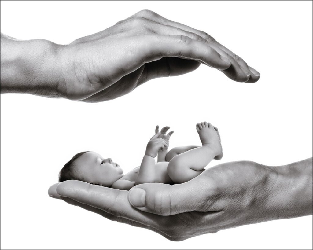 Ein Neugeborenes liegt in der geöffneten Hand eines Erwachsenen, eine zweite Hand hält sich schützend darüber.